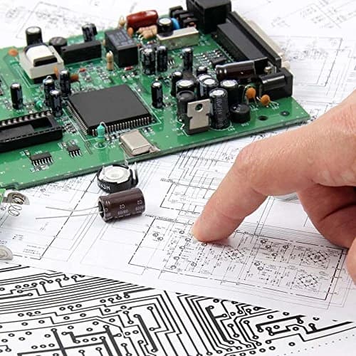 An engineer working on a circuit board over a printed schematic drawing